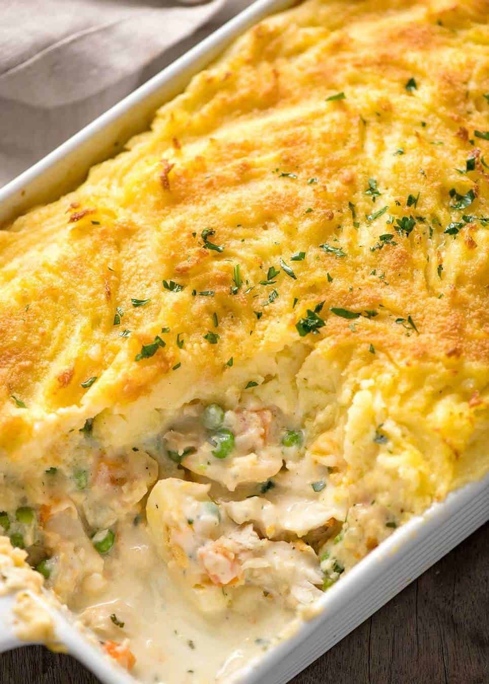 Close up of Fish Pie in white baking dish showing creamy filling with fish flakes