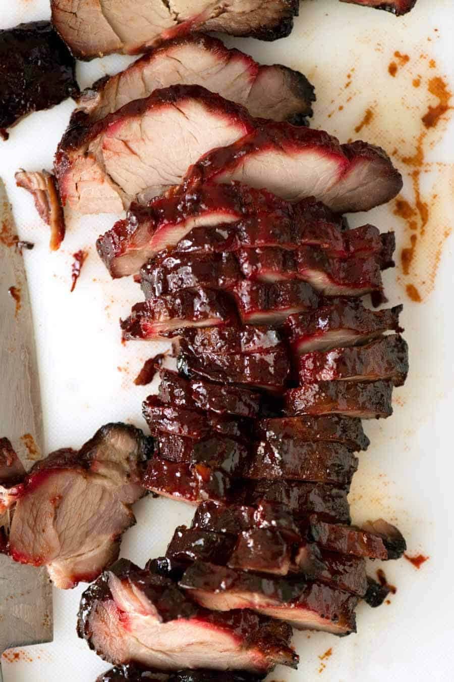 Overhead photo of Char Siu (Chinese Barbecue Pork) sliced on a white cutting board.